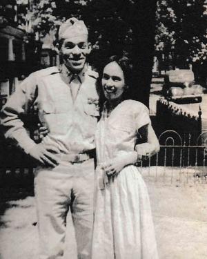 Black-and-white photo of a couple smiling, the man in uniform
