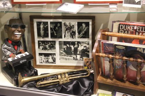 More objects from Black entertainers: a toy of Stevie Wonder, a trumpet, vinyl records.