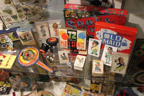 Museum display case of various games and toys using racist imagery: Old Maid is the only fully visible name.