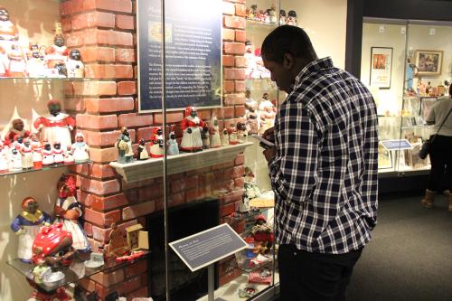 A young visitor observes a museum showcase of “mammy” dolls.