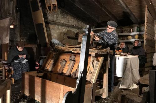 At night, men and women in a room of woodworking tools and products.