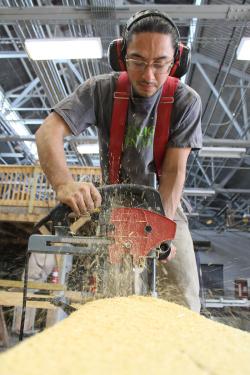 Jiménez cuts a piece of timber with a power tool as sawdust flies.