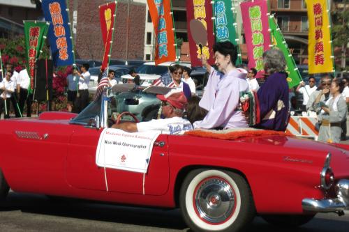 Madame Kansuma waves from her seat in a classic red Thunderbird in the Nisei Week Parade
