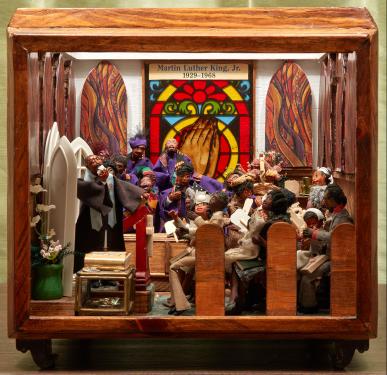 Close-up of a diorama showing Dr. Martin Luther King delivering a sermon to pews of churchgoers, with stained glass windows in the back.