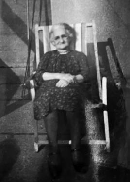 Black-and-white photo of an elderly woman sitting in a beach chair.
