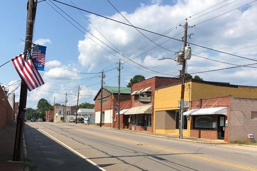 An empty street with a few single-story storefronts and an American flag.