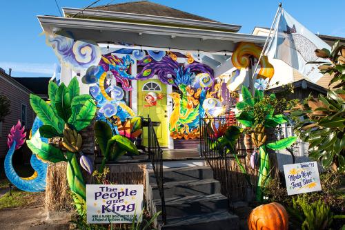 Exterior ofa house decorated with sculptural dragon, palm trees, and other mythical creatures. A lawn sign in front reads THE PEOPLE ARE KING.
