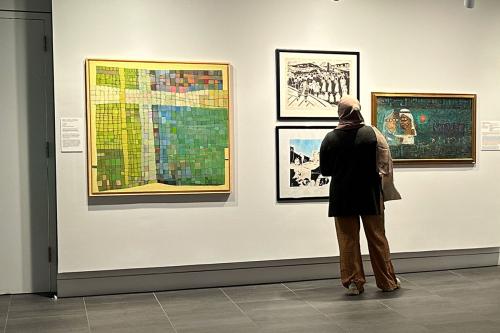 A person examines artwork on a gallery wall.
