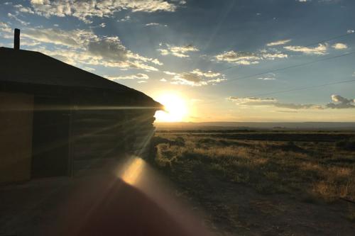 The sun sets behind a wooden structure in the desert.