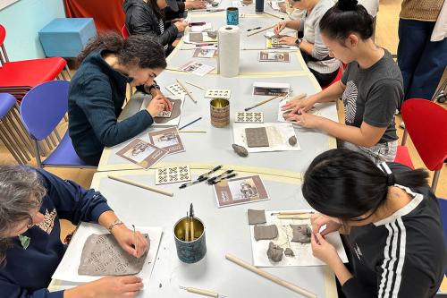 From above, people work on clay projects on a table.