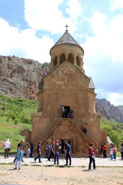 Teens wander around old, beige, stone monastery.