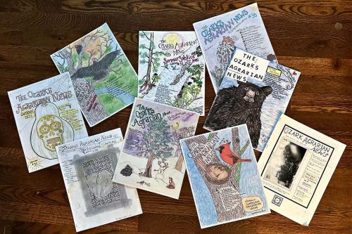 Nine copies of hand-drawn print publication with title in different fonts: The Ozarks Agrarian News. Illustrations feature different animals (bear, cardinal, vulture), and other nature scenes.