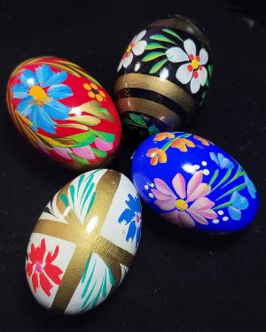 Four intricately painted Easter eggs, each featuring colorful floral designs, displayed against a black background.