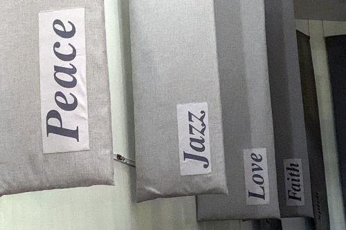 Four gray vertical banners along a wall, each with a single word: Peace, Love, Jazz, Faith.