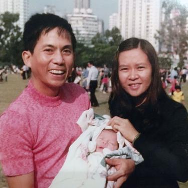 Old photo of two young parents; the father is holding up an infant.