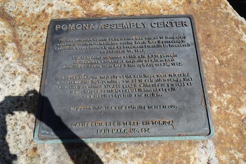 A darkened bronze plaque set in stone with text: Pomona Assembly Center. The Los Angeles County Fairgrounds was one of 15 temporary assembly centers established during World War II pursuant to Executive Order 9066, signed by President Franklin D. Roosevel
