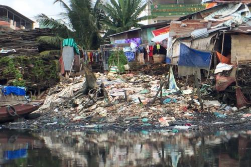 A large mound of garbage along a river bank.