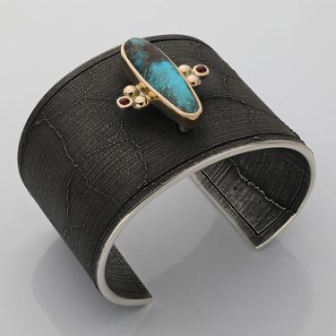 Black cuff bracelet with an oblong turquoise gem in the center.