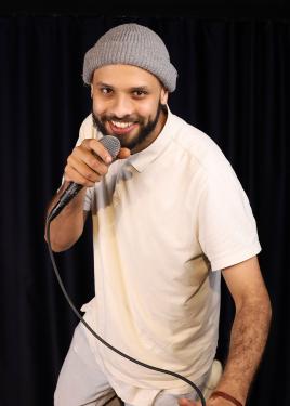 A person smiles, holding a microphone close to their mouth.