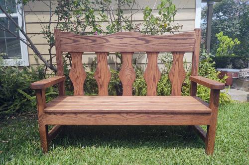 Wooden bench on a lawn outside a home.