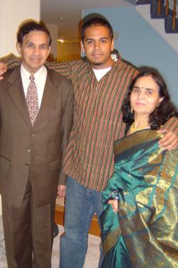Photo of the author posing with his arms around his mother and father. They are all dressed up for a special occasion, the men in Western dress suits and the mom is traditional South Asian dress.
