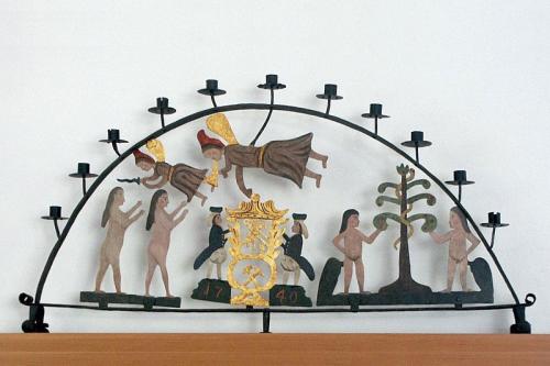 Tin candlestick holder in the shape of a half-circle, with scenes from the bible depicted in the center.