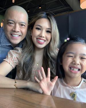 A man, woman, and young girl pose and smile.
