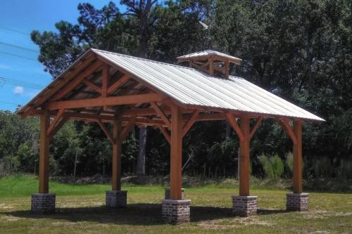 Open-air wooden pavilion structure in a park.