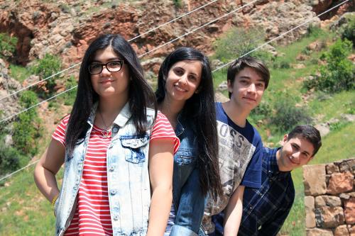 Four teens posing outdoors, fanned out. Alen, in the back, is leaning far to the side.