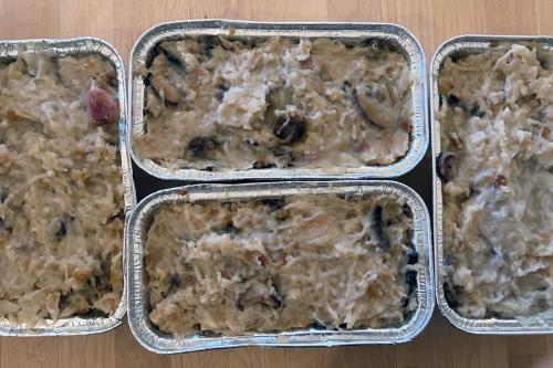 Four small tin loaf pans filled with gray, chunky batter.