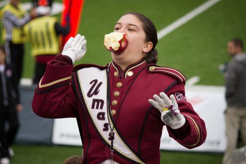 Band member in uniform gestures with a half-eaten apple in her mouth.