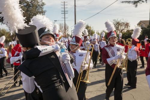 Band members in full uniform on the street break formation to embrace.