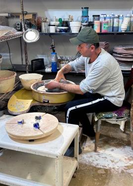 A man works at a pottery wheel.