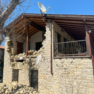 A two-story home with stone exterior, which has crumbled to reveal the interior.