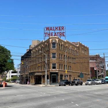 Exterior of a corner brick building, with a large marquee in red on top reading Walker Theatre.