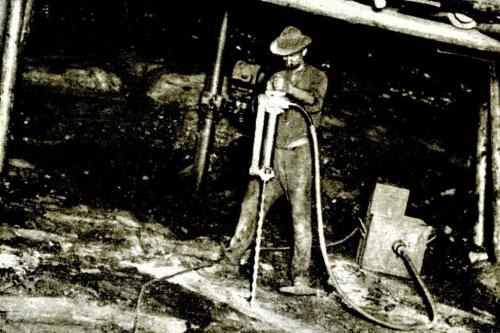 A man works at the mouth of a mine. Black-and-white archival photo.