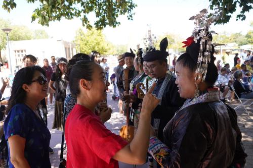 One of the women singers interacts with an audience member, who seems to be interested in her tall silver headpiece.