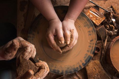 Close-up on the hands of a person working on a traditional Armenia pottery wheel.