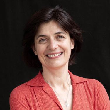 A person with chin-length dark brown hair, red blouse, and broad smile.