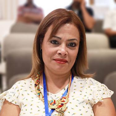 A woman wearing a white blouse and ornate necklace.