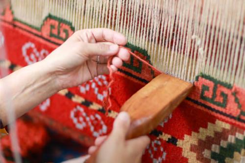A close-up of a woman's hands weaving an intricate design.