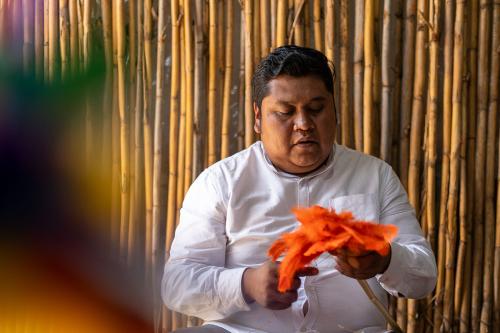A man manipulates bright orange material into the shape of a large flower.
