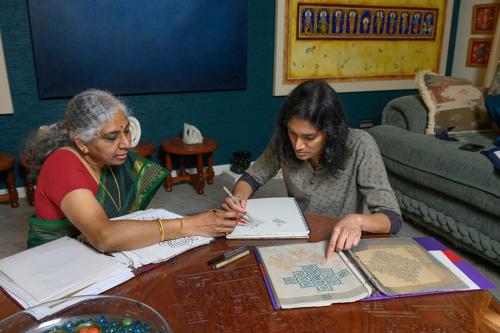 Two women sitting at a table, studying workbooks.