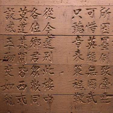 Brown stone wall etched with Chinese characters.