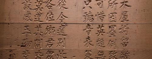 Brown stone wall etched with Chinese characters.