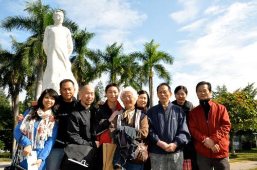 Family posing in front of a white statute and green palm trees.
