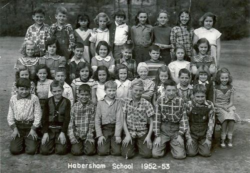Four rows of elementary school children sit outside. Written in white text on the bottom of the frame: Habersham School 1952-53. Black-and-white photograph. 