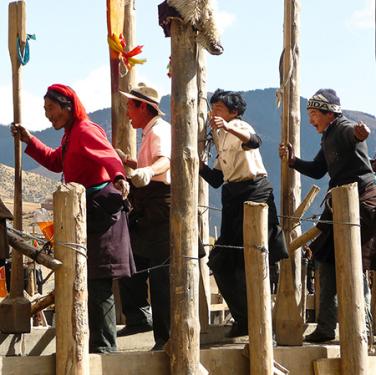 Men and women jump on a wall in progress in a choreographed wall-building dance. Photo by Dawa Drolma