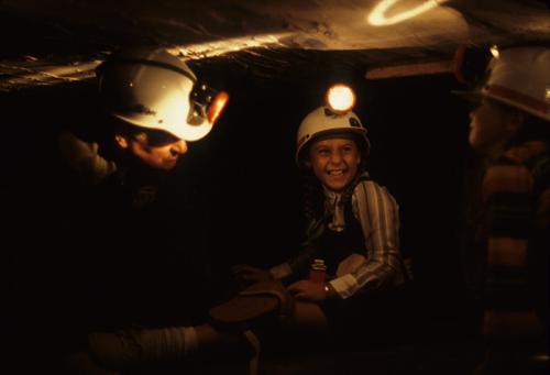 A coal miner from West Virginia shows two young visitors the challenges of working in the confined spaces of a simulated coal mine.