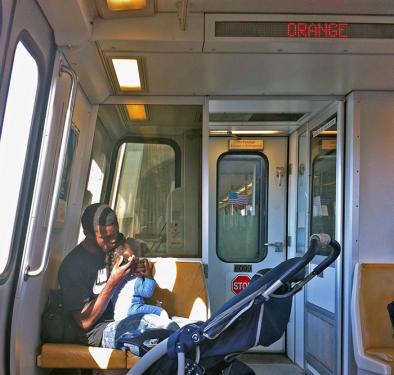 A young man braids his daughter&rsquo;s hair on the Metro in Washington, D.C.